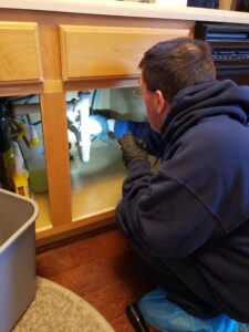 Professional pest control technician in protective suit spraying exterior for insect prevention.